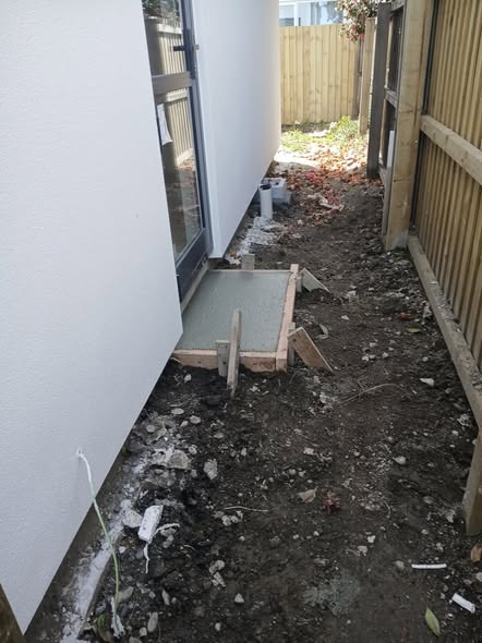 Narrow concrete side path with timber formwork boxed between a new home and a timber fence — concreting in Christchurch.